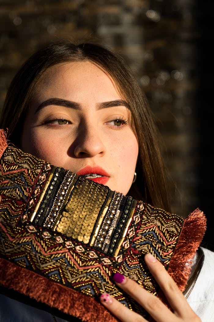 A stylish portrait of a woman holding an ornate clutch with a sunlight backdrop.